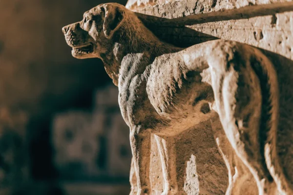 Ancient Roman stone relief carving of a large molosser war dog in dramatic museum lighting